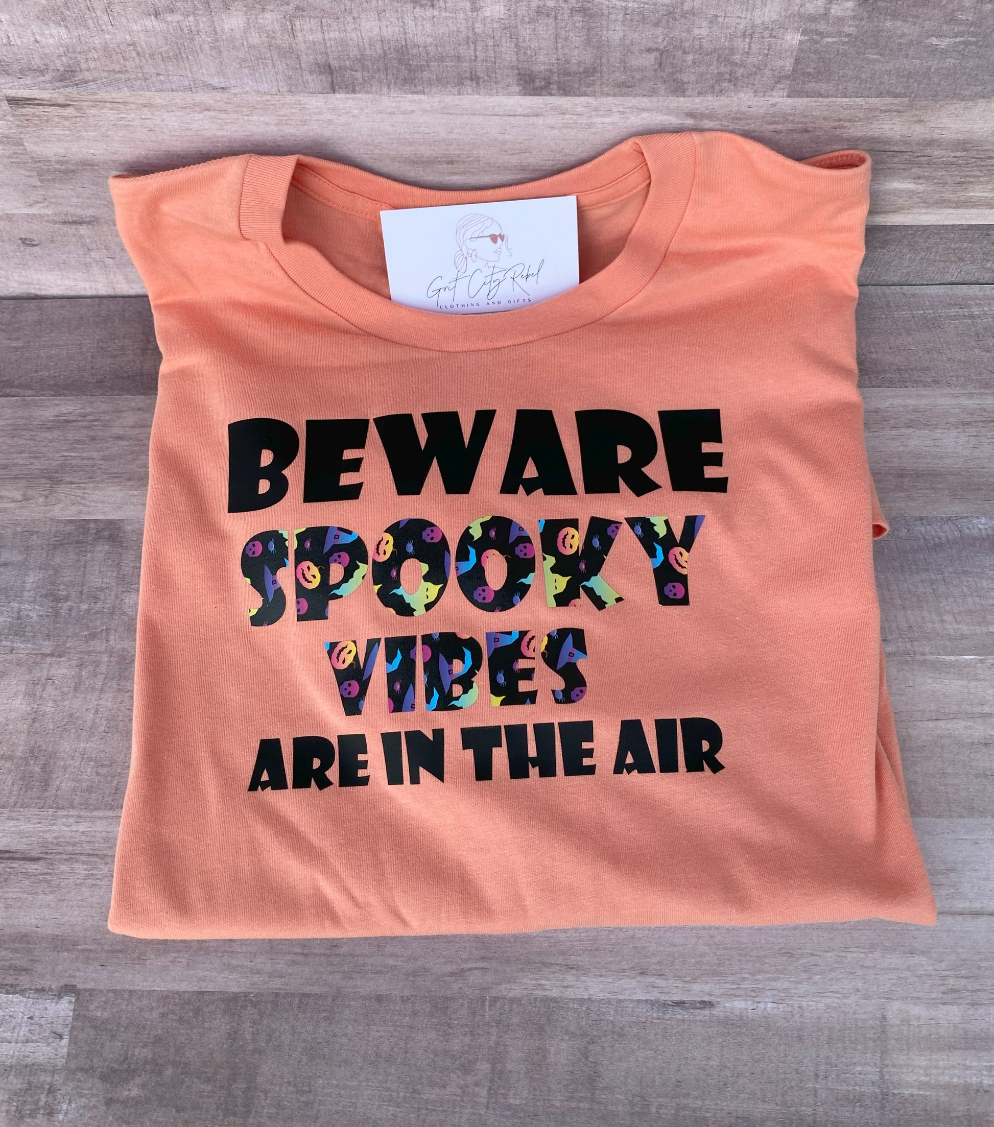 Grit City Rebel sunset orange unisex t-shirt with the phrase beware spooky vibes are in the air.  Available in sizes small to 3xl.