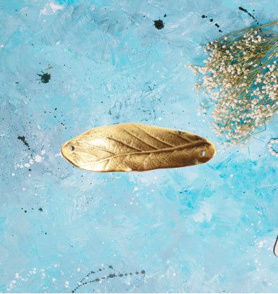 a leaf charm in antique gold. the charm has a slight curve to utilize as a bracelet spacer. the charm is approximatley 2 inches long