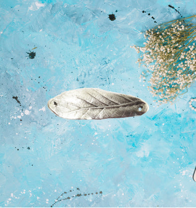 a leaf charm in antique silver. the charm has a slight curve to utilize as a bracelet spacer. the charm is approximatley 2 inches long