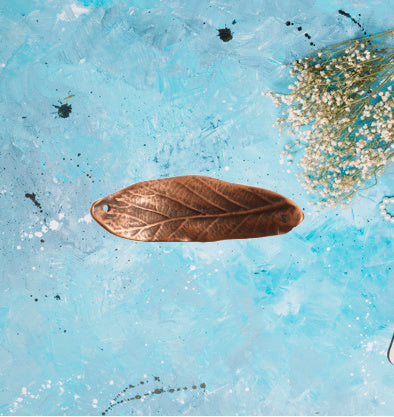 a leaf charm in antique bronze. the charm has a slight curve to utilize as a bracelet spacer. the charm is approximatley 2 inches long