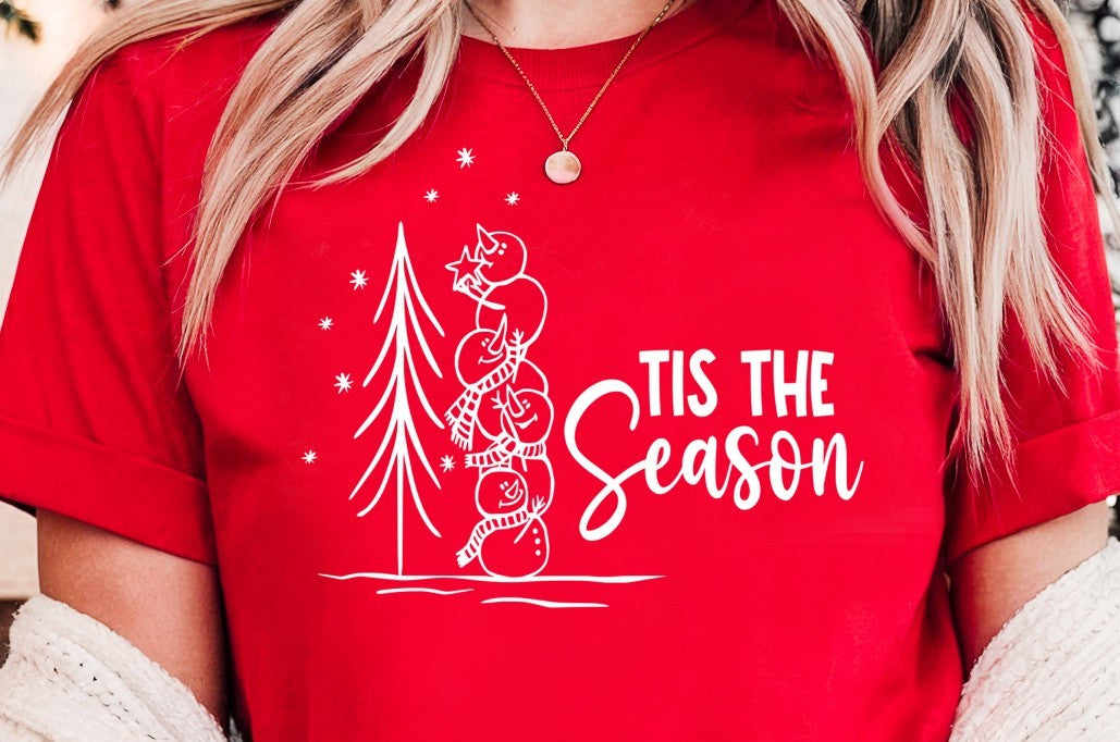 November 2025 VIP T-Shirt of the Month - Phrase Tis The Season with a graphic of Stacked Snowmen placing a Star on an Outdoor Tree