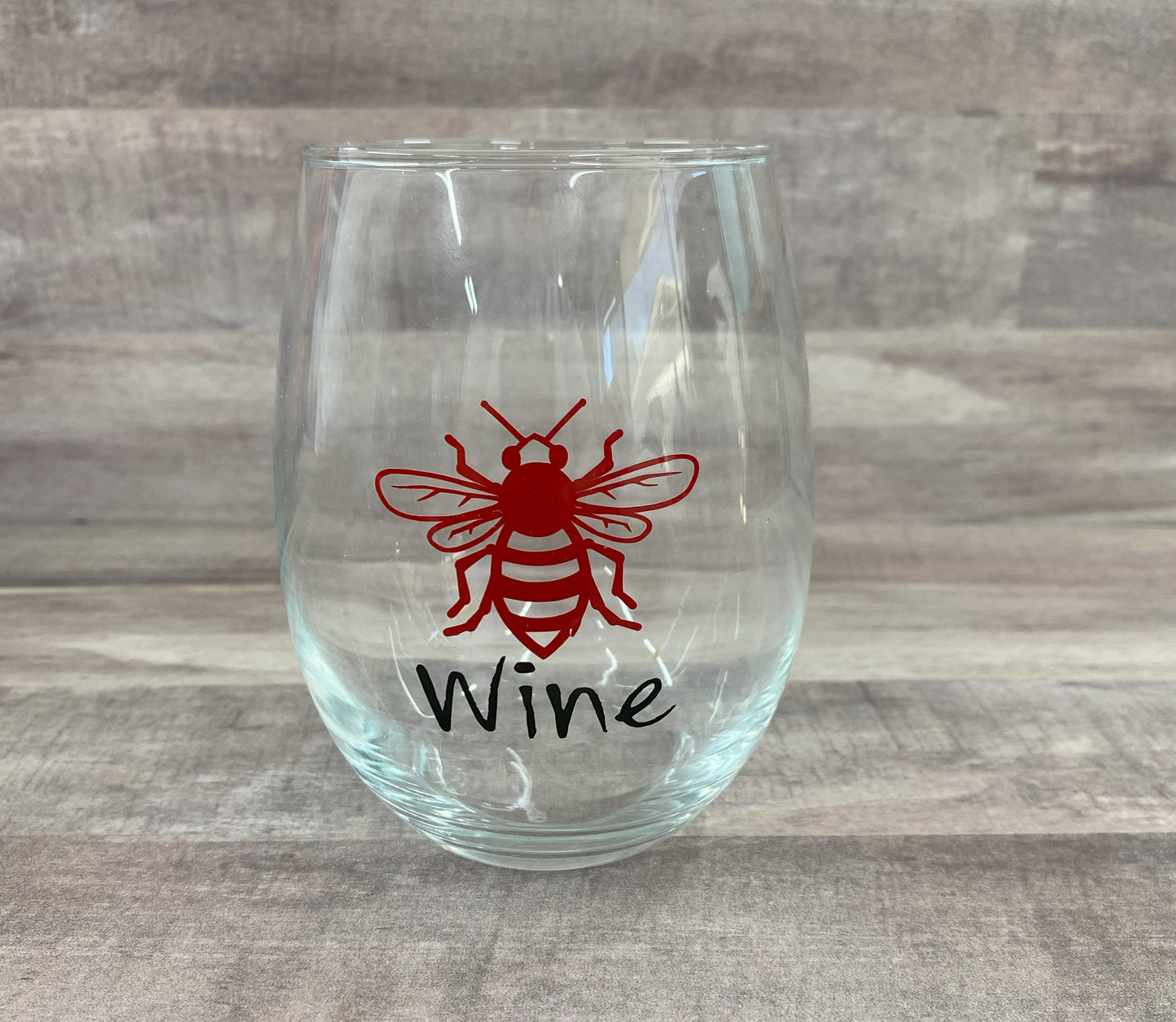 Stemless 15oz wine glass with a red bee outline and the phrase "wine" in black writing. Customizable. Designed by Grit City Rebel.