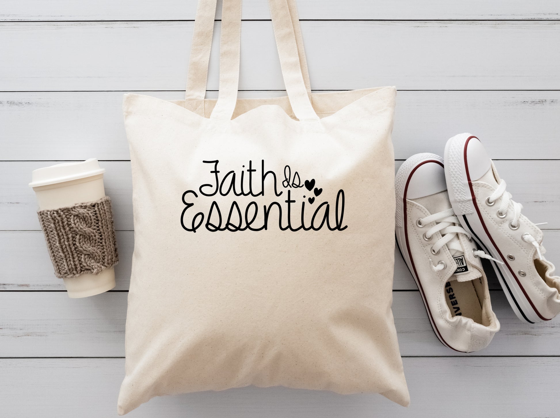 cream colored cloth reusable tote bag with the saying Faithis essential 