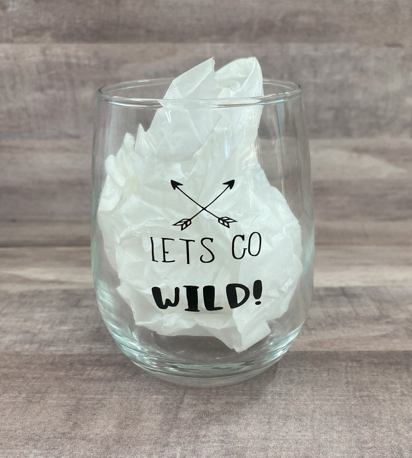 Stemless 15oz wine glass with the phrase lets go wild in black writing with crossed arrows Customizable. Designed by Grit City Rebel.