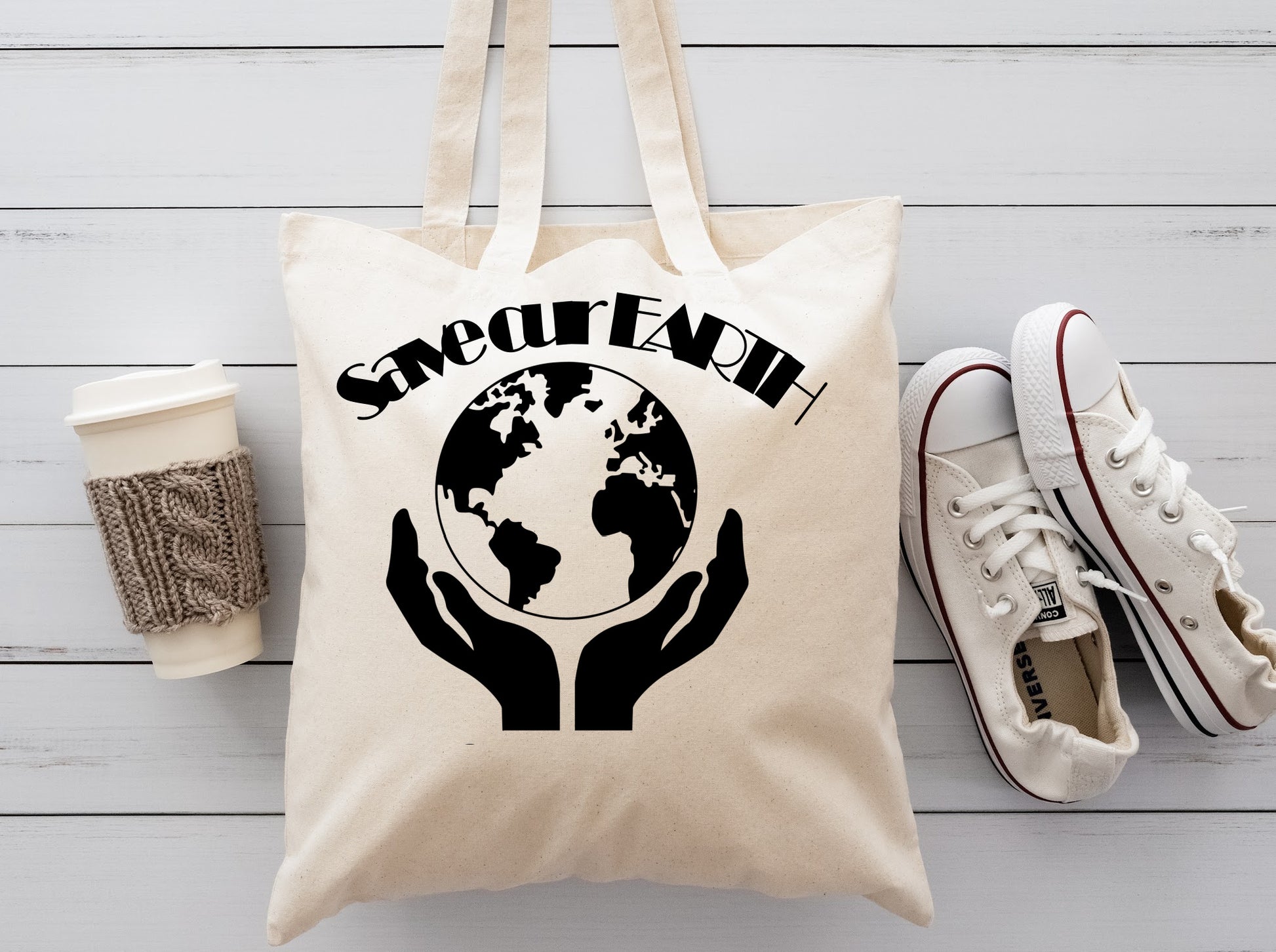 Cream colored fabric reusable tote bag with hands holding up the world