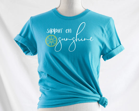 Grit City Rebel aqua unisex t-shirt with the phrase sippin' on sunshine with a lemon outling.  white writing lemon yellow. sizes small to 3x.