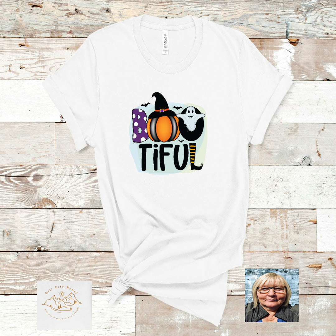 white unisex Tshirt with a colorful design of a pumpkin and ghost with the word BOOTIFUL