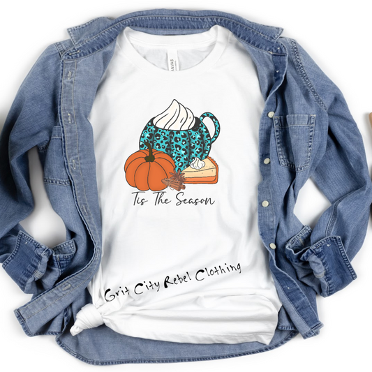 Big Teal mug with black spots and whipping cream on top with a orange pumkin on the side and in black tis the season on a white unisex Tshirt