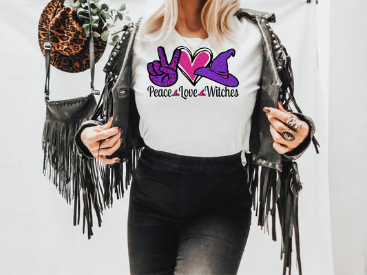 white short sleeve unisex T-Shirt with peace sign purple pinkcolor, heart in pink, witch hat in purple and pink with the words Peace Love Witches under each design