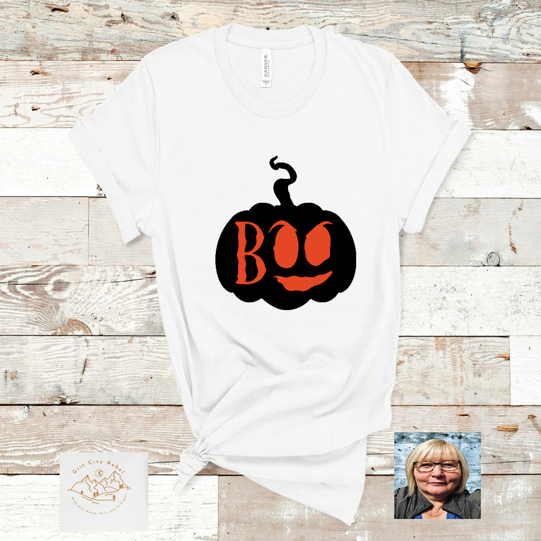 white short sleeve unisex T-Shirt with a black pumpkin and the woord Boo in orange cut out.