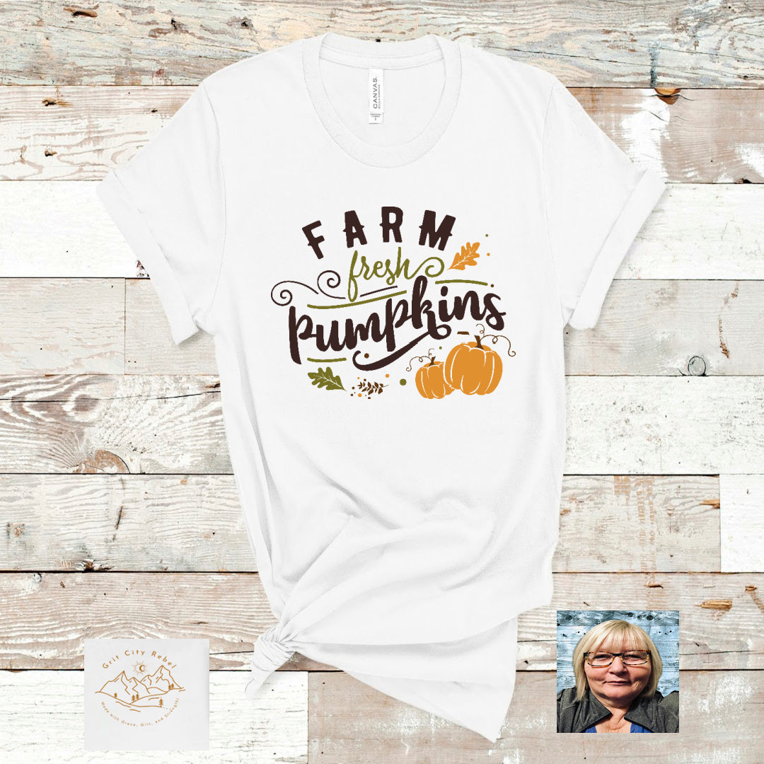 white short sleeve unisex T-Shirt with the saying Farm Fresh Pumpkins in green and black writting with orange pumpkin accents